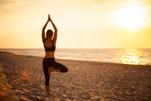woman does yoga at beach in alcohol rehab