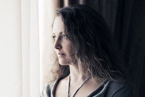 woman looking out window needs Mental Health Treatment