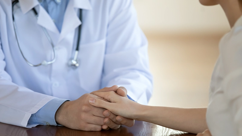A doctor comforts a young female patient with empathy while explaining her diagnosis.