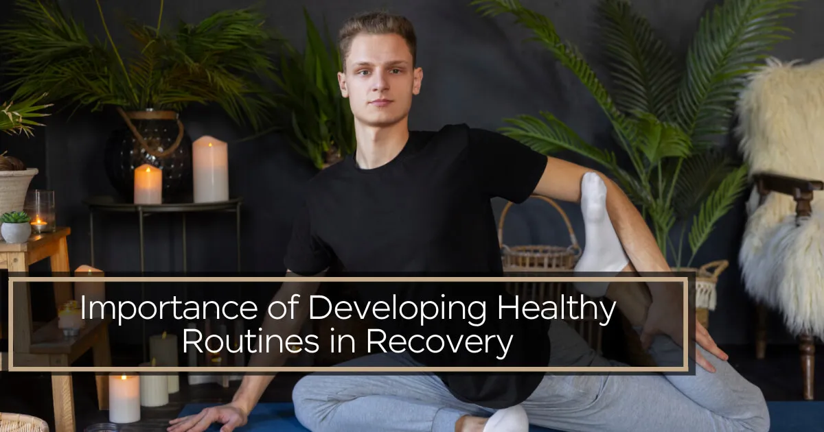 A young man in a black t-shirt and grey joggers performing a yoga stretch on a blue mat.