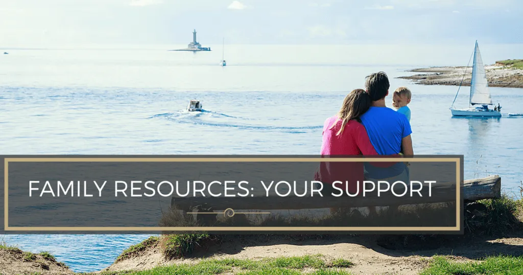Family on a bench overlooking the ocean with sailboats and a lighthouse.