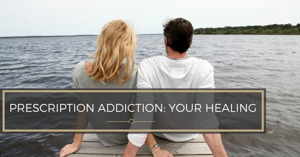Couple sitting on a wooden dock overlooking the water.