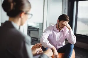 Distressed man on a beanbag chair talking to a therapist.