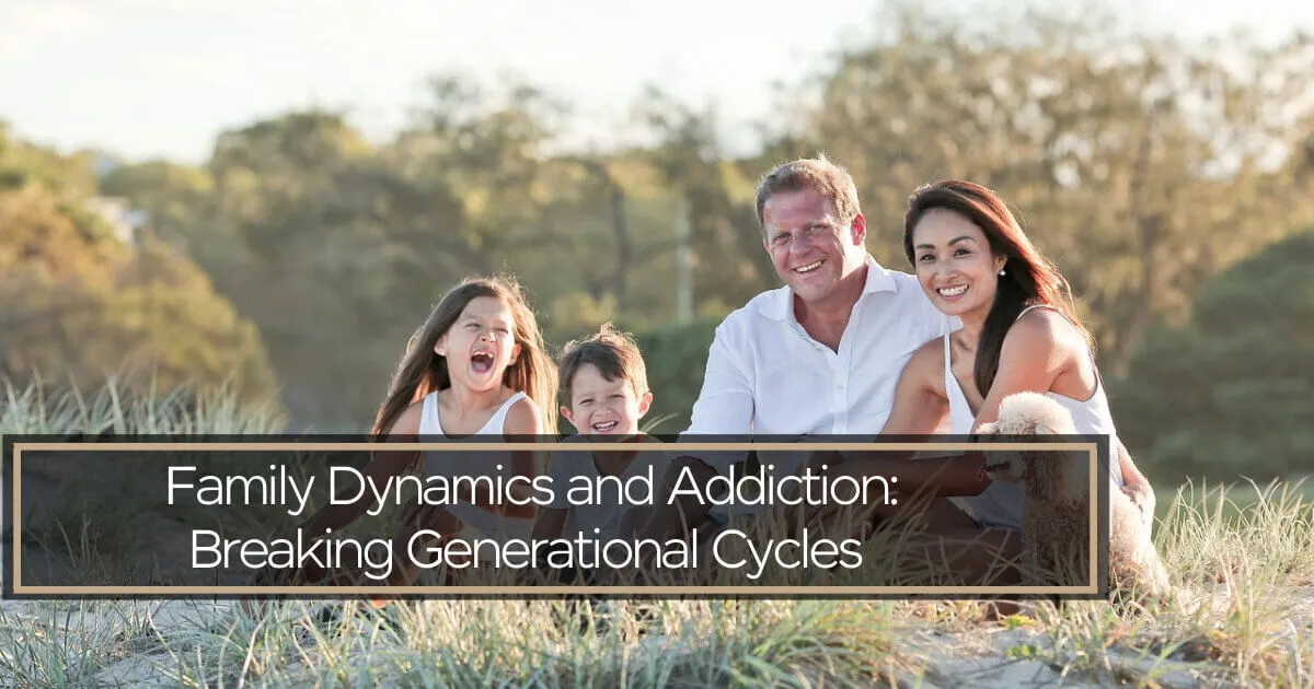 A smiling family of four with a small dog sits together in a grassy, sunlit outdoor setting.