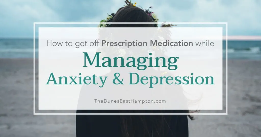 A woman stands on a beach facing the ocean.
